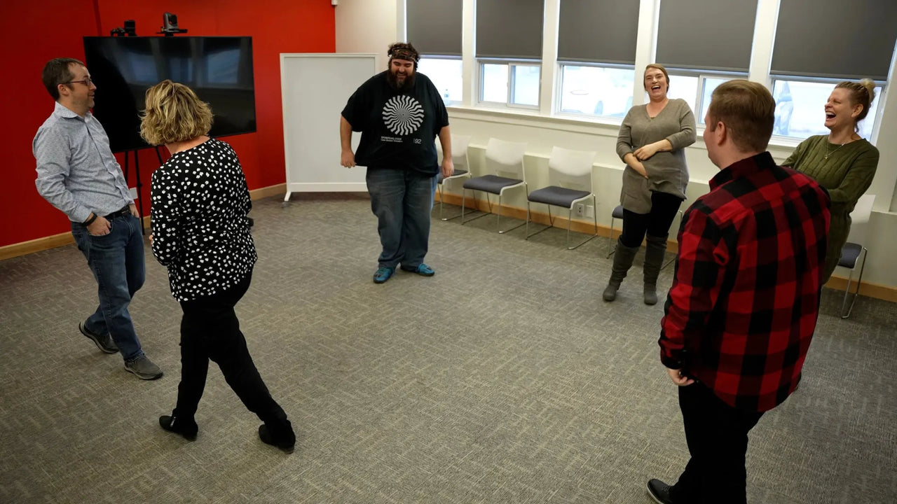 Team in a circle laughing during a comedy team building workshop
